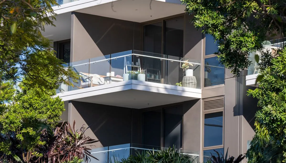 Modern building with glass balconies and lush foliage