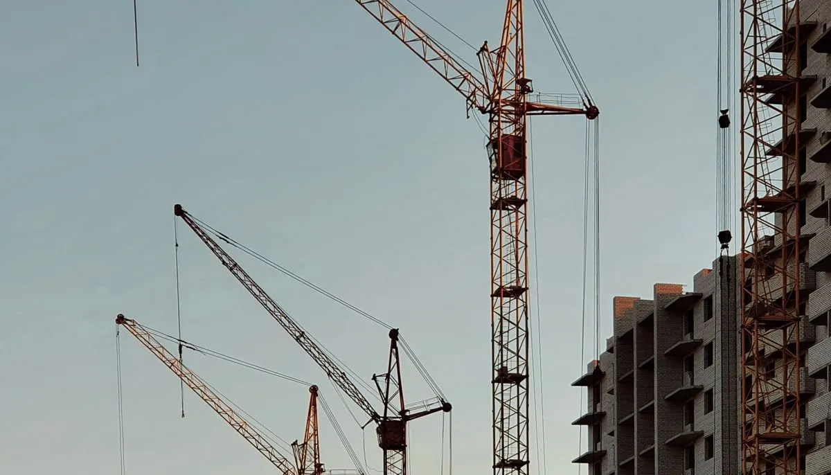 Blocks of flats and cranes machinery against the sky